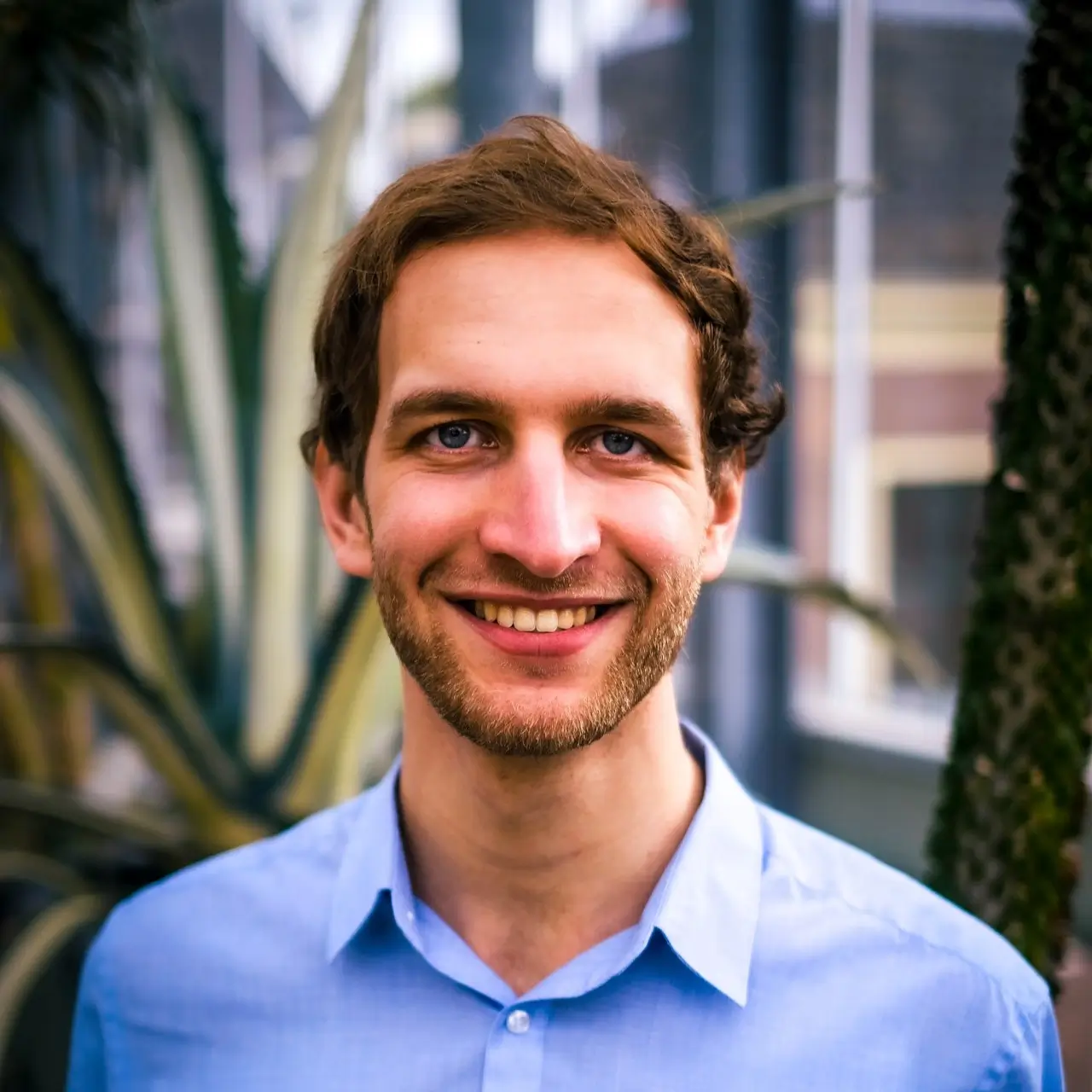 Een portretfoto van Wessel met planten in de achtergrond