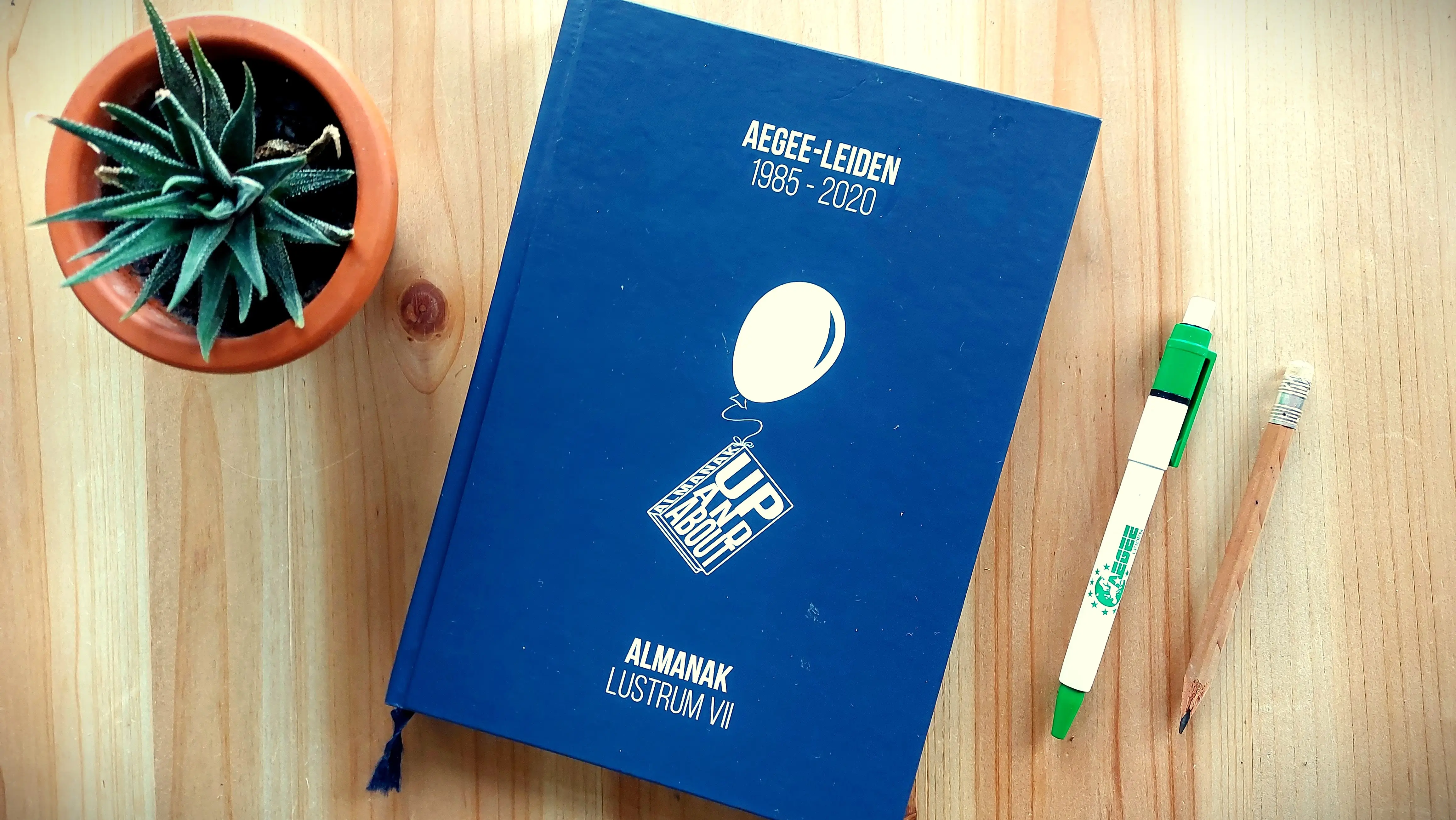 A copy of the AEGEE-Leiden almanac on a wooden table.
