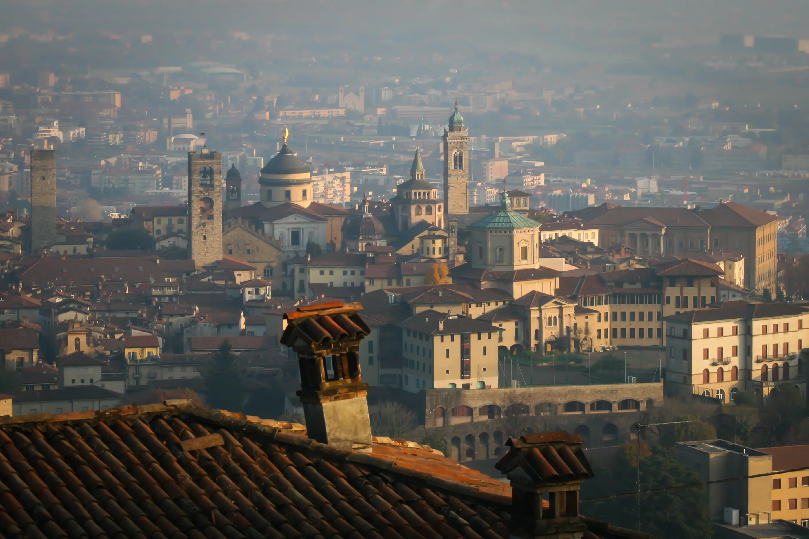 A view of the Città Alta in Bergamo, Italy, with a chimney in the foreground.